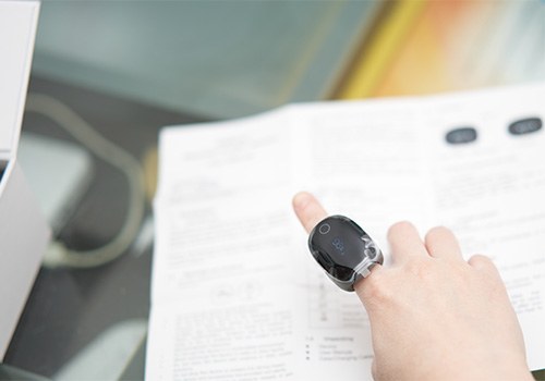 Person wearing oximeter ring on their finger