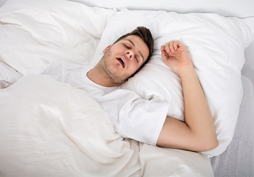 Snoring man lying on his back in bed